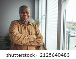 Small photo of African American Senior Man at home Portrait. Smiling senior man looking at camera. Portrait of black confident man at home. Portrait of a senior man standing against a grey background