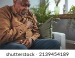 Small photo of Upset older man touching chest, talking on phone, unhappy mature male having heart attack, lonely grandfather suffering from heartache disease at home, feeling pain, sitting alone.