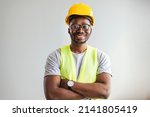 Small photo of Happy African Builder Workman Standing Pleased Crossing Hands Posing On Gray Studio Background. Copy Space. Industrial engineer