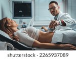 Small photo of Pregnant woman undergoing ultrasound test at gynecologist office. Closeup of male doctor moving ultrasound probe on pregnant woman's stomach in hospital. Doctor and patient. Ultrasound equipment.