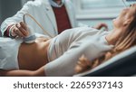 Small photo of Mid adult male doctor using ultrasound scanner. Ultrasound exam. Doctor's hands on a woman's stomach, ultrasound of the abdominal cavity, close-up. Diagnosis of diseases of the genitourinary system