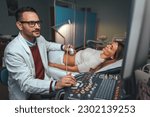 Small photo of Selective focus on ultrasound scanner device in the hand of a professional doctor examining his patient doing abdominal ultrasound scanning sonogram sonography sonographer early pregnancy