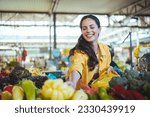 Beautiful young woman buying vegetables. Young cheerful woman at the market. Raw food, veggie concept. Portrait of smiling good looking girl in casual clothing
