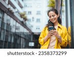 Small photo of A businesswoman reading something funny on her mobile phone on the street while going back home from work. Connected city worker. Close up of a young lady using a phone while on the street