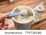 Small photo of Powder milk and blue spoon on light background close-up. Milk powder for baby in measuring spoon on can. Powdered milk with spoon for baby. Baby Milk Formula and Baby Bottles.