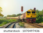 Small photo of Procession train led by Yellow Diesel electric Locomotives at curve and sail through rail chopper with traffic light before entering Ratchaburi station of Thailand.