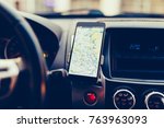 The map on the phone in the background of the dashboard. Black mobile phone with map gps navigation fixed in the mounting. Vintage style photo