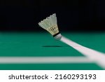 Shuttlecock floating on a green badminton court. Background, taken in low light.