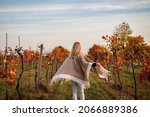Happy boho woman with poncho running in autumn vineyard. Fall season in winery