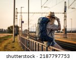 Travel at vacation. Woman with backpack waiting for train at railway station