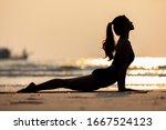 Silhouette of Athletic Asian young woman practice Cobra Pose on the sand and beach with sunset beautiful sea in Tropical island,Feeling comfortable and relax in holiday,Vacations Yoga Concept
