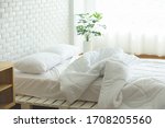 Small photo of Messed bed with white pillow and blanket with natural light in bedroom in the morning,Messy bed after wake up,Messy bed and Cozy Bedroom Concept