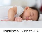 Small photo of Happy asian newborn baby lying sleeps on a white bed comfortable and safety.Cute Asian newborn sleeping and napping at warmth place deep sleep and fresh breathing.Newborn Baby Sleep concept