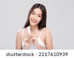 Small photo of Beautiful Young Asian Woman Holding luxury white cream tube smile feeling so happy with healthy Clean and Fresh skin,isolated on gray background. Self care of Beauty Cosmetics spa and treatment