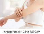 Beautiful Asian young woman apply cream or lotion on her arm for protect dry skin for moisturizing on skin. Healthy skin of young female doing self care at home. Woman self care concept