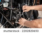 Mechanic using a Hex key or Allen wrench to remove Motorcycle rear Hydraulic brake pump, working in garage .maintenance and repair motorcycle concept .selective focus