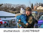 Small photo of Medyka, Poland, March 2022: Polish soldier carries a refugee baby. Refugees from Ukraine escaping from war. Ukrainian refugees on crossing the border to Poland. Ukrainians fleeing the war.
