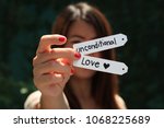 Small photo of a woman holds the paper tags of unconditional love or unfailing love concept background