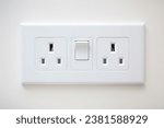 White wall mounted socket board with two electrical sockets and a switch. The socket board is isolated on a white background