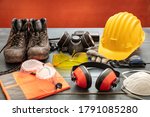 Work safety protection equipment. Industrial protective gear on wooden table, red color background. Construction site health and safety concept