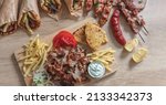 Small photo of Gyro Greek sliced meat traditional street food. Ethnic dish, pita bread, tzatziki yogurt potato and onion on wooden table, top view