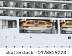 Small photo of IJmuiden, the Netherlands - June 15th 2019: Seven Seas Explorer leaving IJmuiden Sea lock. Seven Seas Explorer is operated by Regent Seven Seas Cruise Line. Detail of balcony staterooms, safety vessel