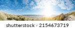 Small photo of Panoramic landscape background banner panorama of sand dune, beach and ocean North Sea with blue sky, clouds, gulls and sunbeams
