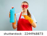 Woman in red mask, rubber gloves and apron holding cleaning agent bottle