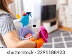 Woman in rubber gloves with basket of cleaning supplies ready to clean up