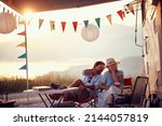 Couple in love. Sitting in front of camper rv. Having fun. Outdoors summer party. Fun, togetherness, nature concept.