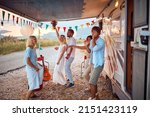 Newlyweds and friends dancing in front of decorated camper rv. Celebration of newlywed couple. Wedding ceremony, love, nature concept