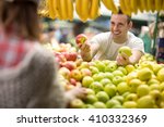 salesman offers an apple at street market