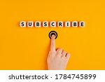 Male hand pressing subscription button with the word subscribe written on wooden blocks. Online registration concept.