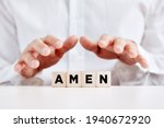 Christian man holds his hands over the wooden cubes with the word amen.