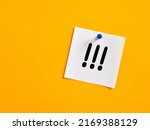 Small photo of Three handwritten exclamation marks on a note paper pinned on a yellow board. Important notice concept.