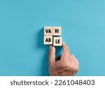 Small photo of Variability, variation, flexibility and change in business concept. Male hand placing wooden blocks into a square shape to assemble the word variable.