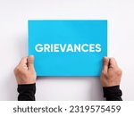 Small photo of Employee or customer grievance. Grievance procedure business concept. Male hand holding a blue paper with the word grievances.