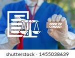 Small photo of Medical worker holding wooden block with code of conduct collocation and touching document sheet with scales icon. Code of conduct health care concept.