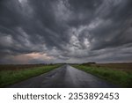 WEATHER - Dramatic black rain clouds over fields and country road