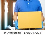 Small photo of parcel delivery man wear protective gloves blue, protect Hygiene germs and bacteria of a package through a service send to home. hand holding consign and submission customer accepting a of box.