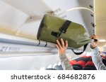 Passenger woman putting luggage into overhead locker on airplane (Selective focus)