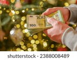 euro money in hands on a Christmas trees background.Christmas and New Year expenses. Spending on gifts and Christmas decor.Expenses during the winter holidays