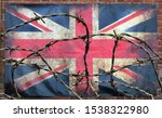 Small photo of barbed wire in front of an old stained dirty union jack british flag with dark crumpled edges on a brick wall background brexit freedom of movement isolationist concept