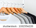 close up collection of black, gray and white color (monochrome) t-shirt hanging on wooden clothes hanger in closet or clothing rack over white background, copy space
