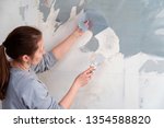 woman tears off Wallpaper, removing Wallpaper from the wall with a spatula, the process of updating the wall room repair. with free text space