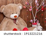 beautiful backdrop for a Valentine's Day photo shoot with a huge teddy bear, a wooden fireplace with candles and flowers, and a tree with red and pink hearts. Romantic mood for the holiday of lovers.