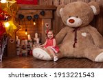 happy little girl in beautiful backdrop for Valentine's Day photo shoot with huge teddy bear, wooden fireplace with candles, with a bunch of balloons and flowers, and tree with red and pink hearts.