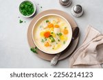 Creamy fish chowder soup in bowl on concrete background. Top view.