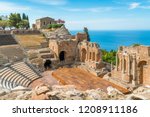 Ruins of the Ancient Greek Theater in Taormina on a sunny summer day with the mediterranean sea. Province of Messina, Sicily, southern Italy.
