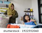 muslim asian mother and child girl little helper in laundry room near washing machine